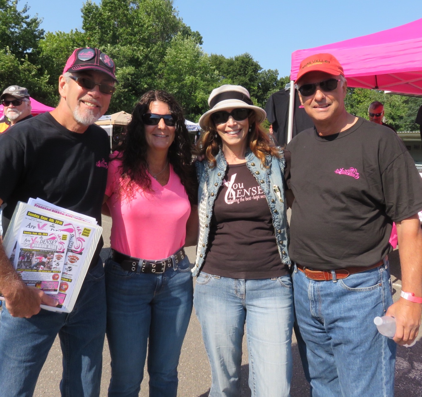 Four supporters, one holding ride flyers, by the pink tents