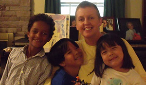 Collin smiling with three young children
