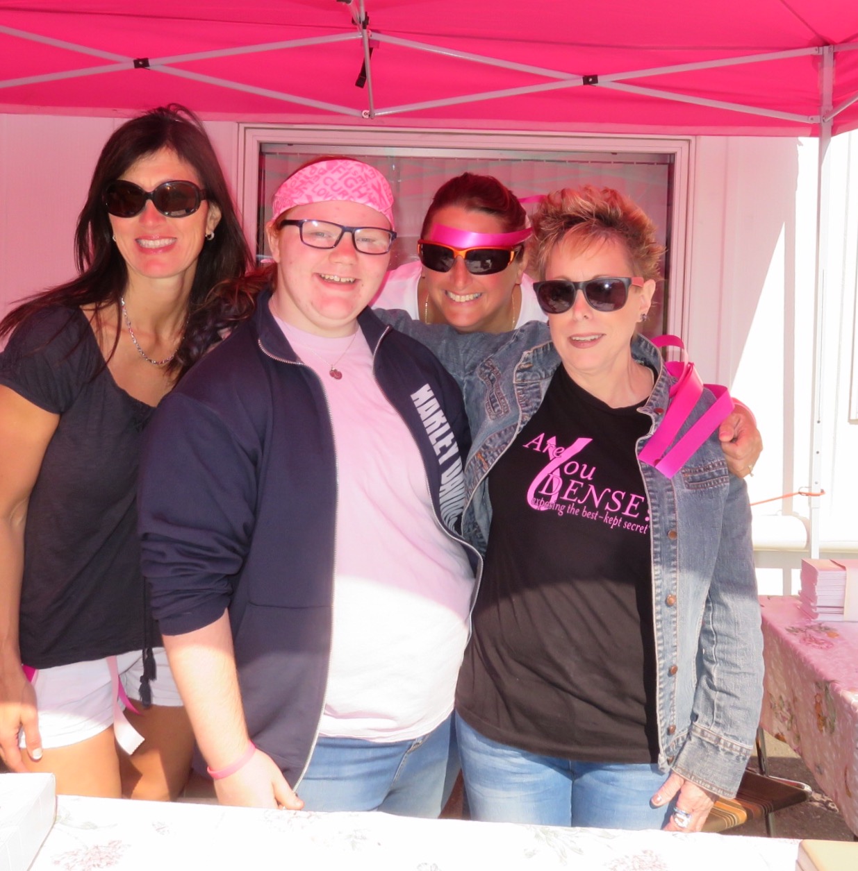 Four volunteers in sunglasses at the pink registration tent