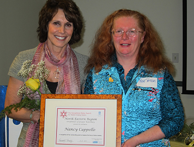 Dr. Cappello holding flowers and her framed Soroptimist award certificate beside Rose Petruzzi