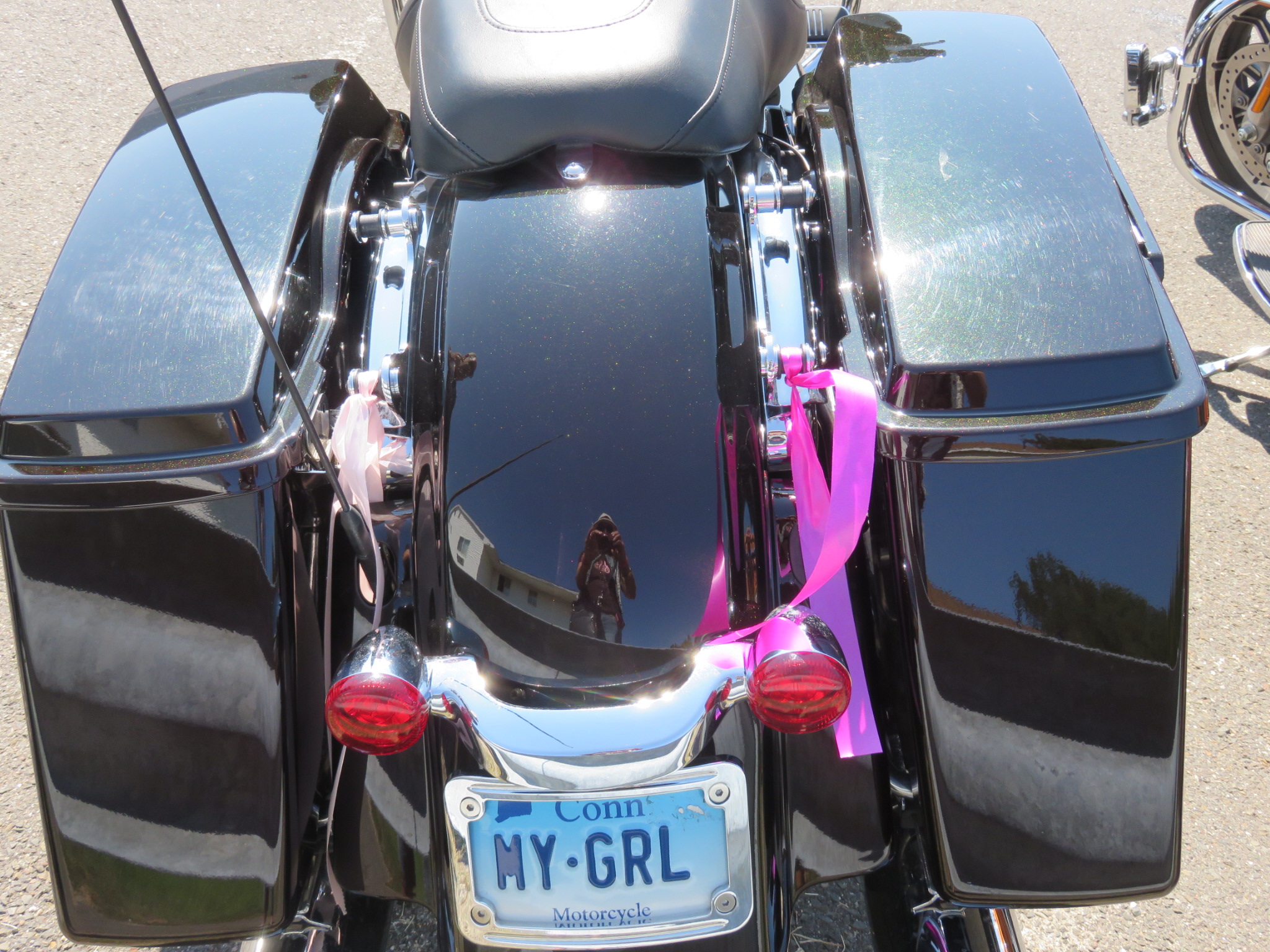 Pink ribbons tied to a black motorcycle with a MY-GRL license plate