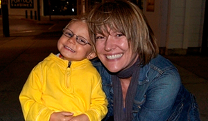 MaryBeth hugging a young child in a yellow jacket