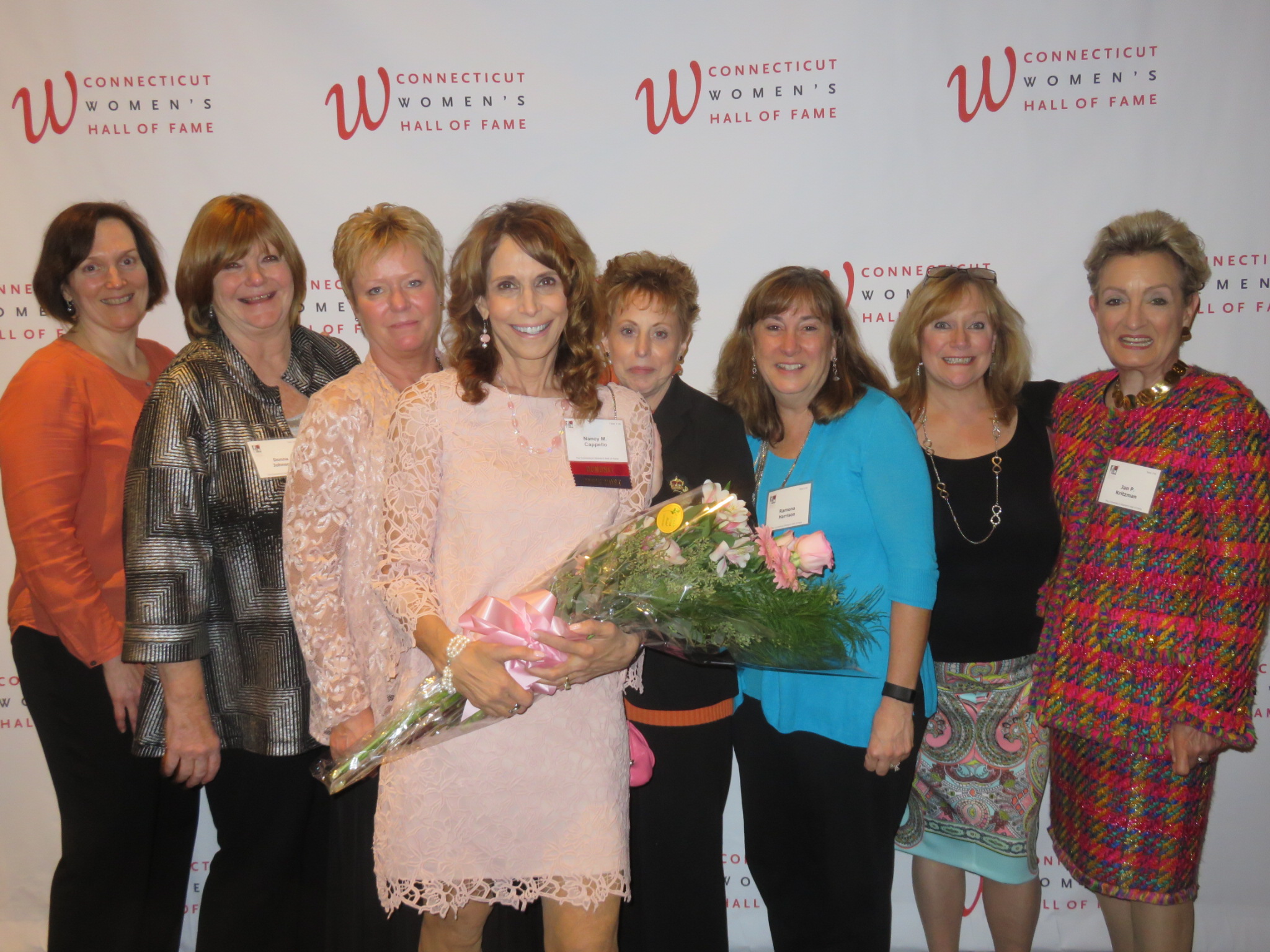 Dr. Cappello holding a bouquet with friends and colleagues at the Connecticut Women's Hall of Fame backdrop