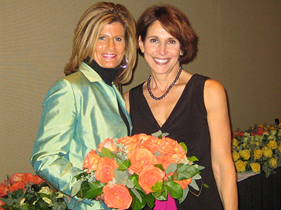 Ruth Loiseau holding a bouquet of orange roses beside Dr. Cappello