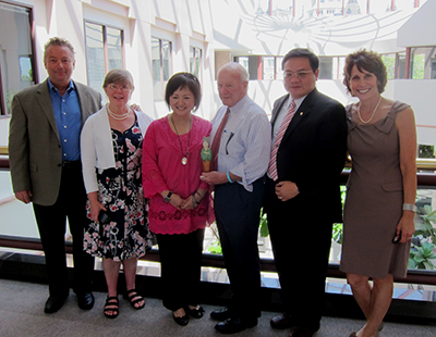 Dr. Pai-Jung Huang with Senator Crisco, Dr. Cappello and guests in a sunlit atrium