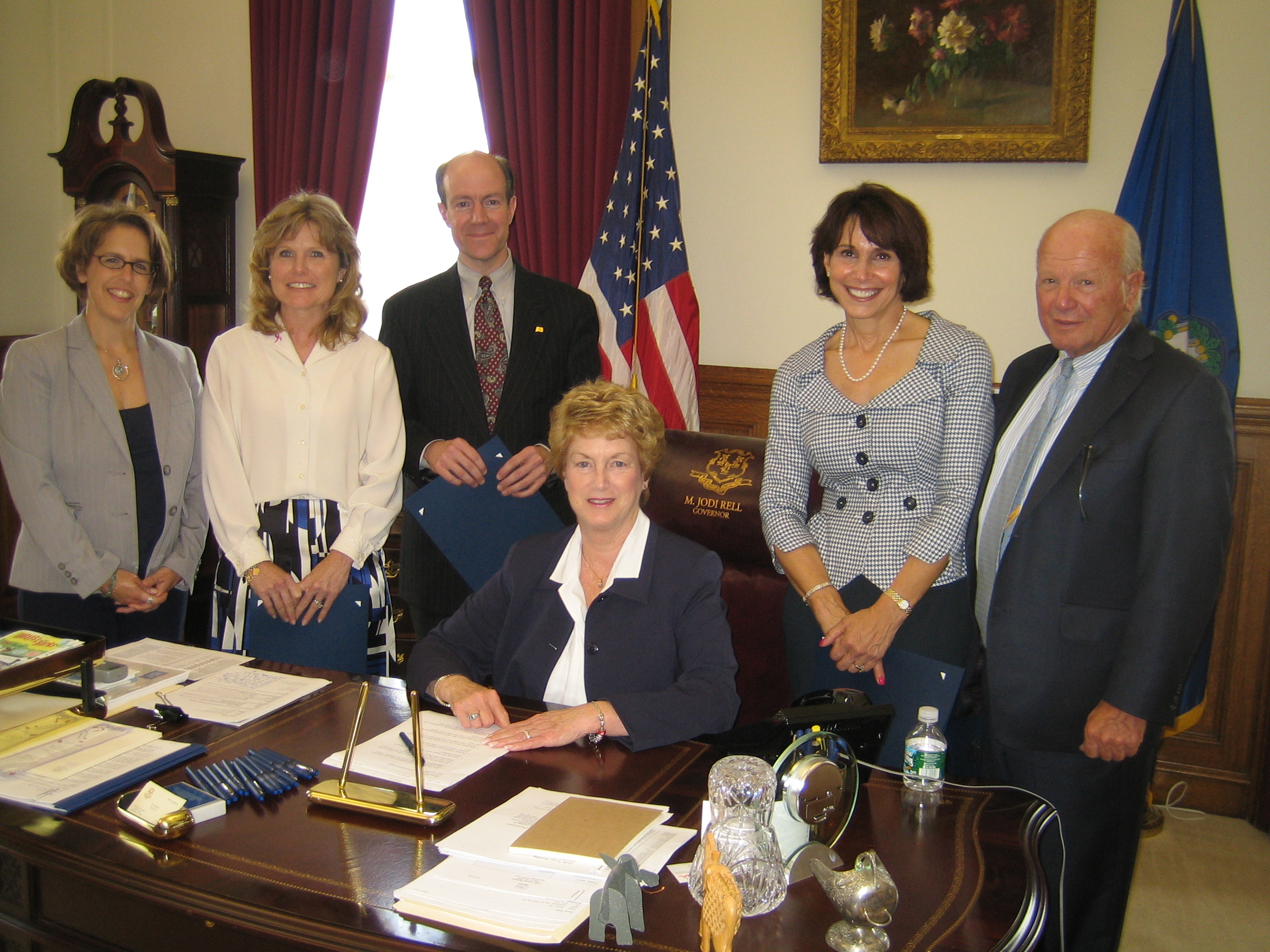 Governor Jodi Rell at her desk surrounded by advocates at the 2009 breast density bill signing