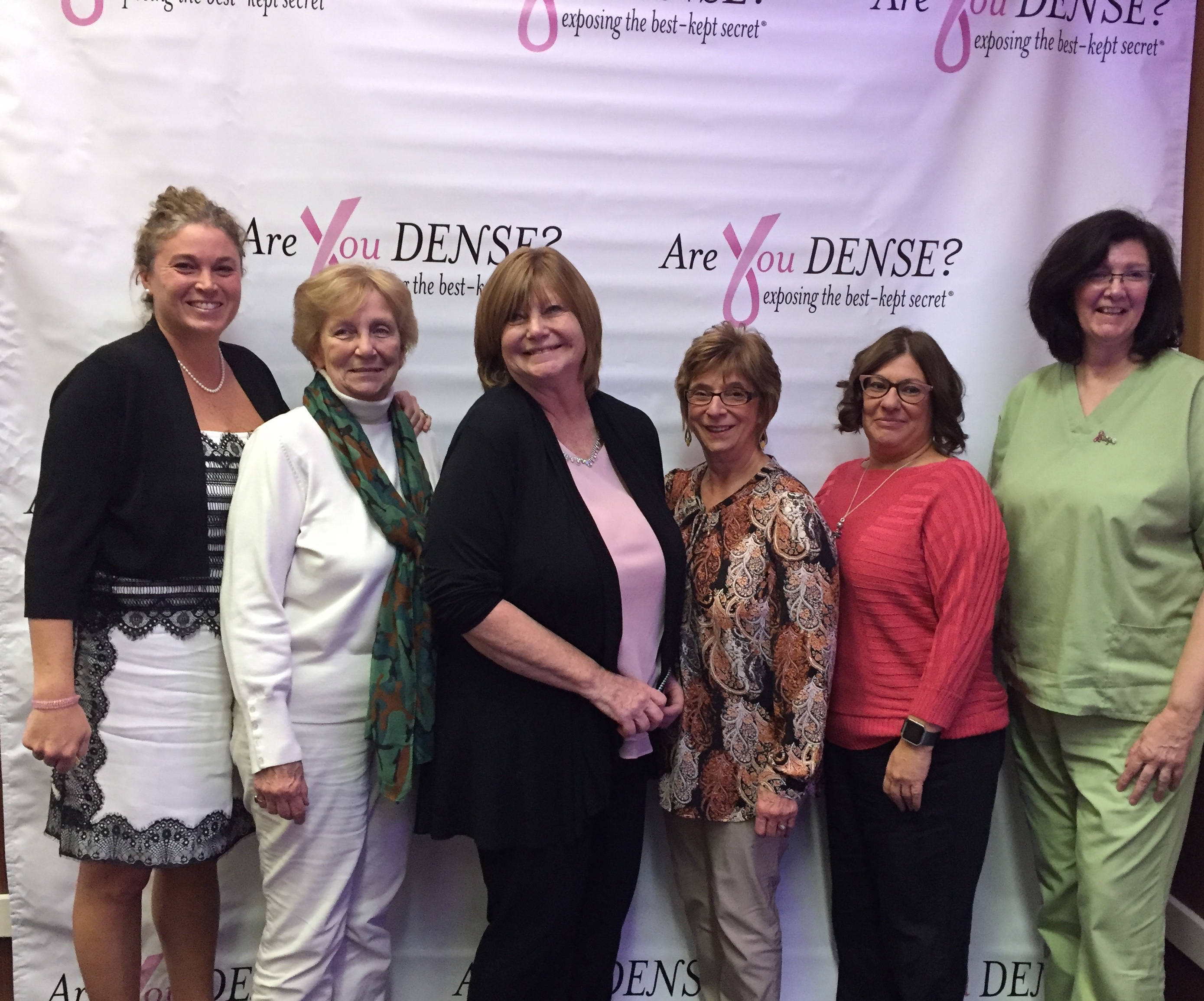 Six guests posing at the Are You Dense? backdrop