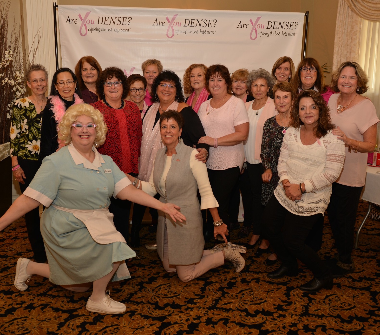 Brunch guests and auctioneer Earlene Babcock, in costume, posing at the Are You Dense? backdrop