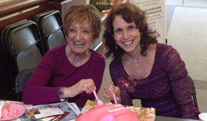 Jan and a friend celebrating at a table with a pink cake