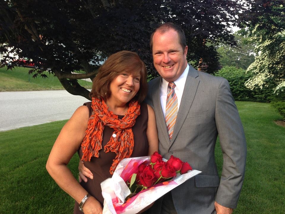 Lori Ann holding red roses beside her husband David