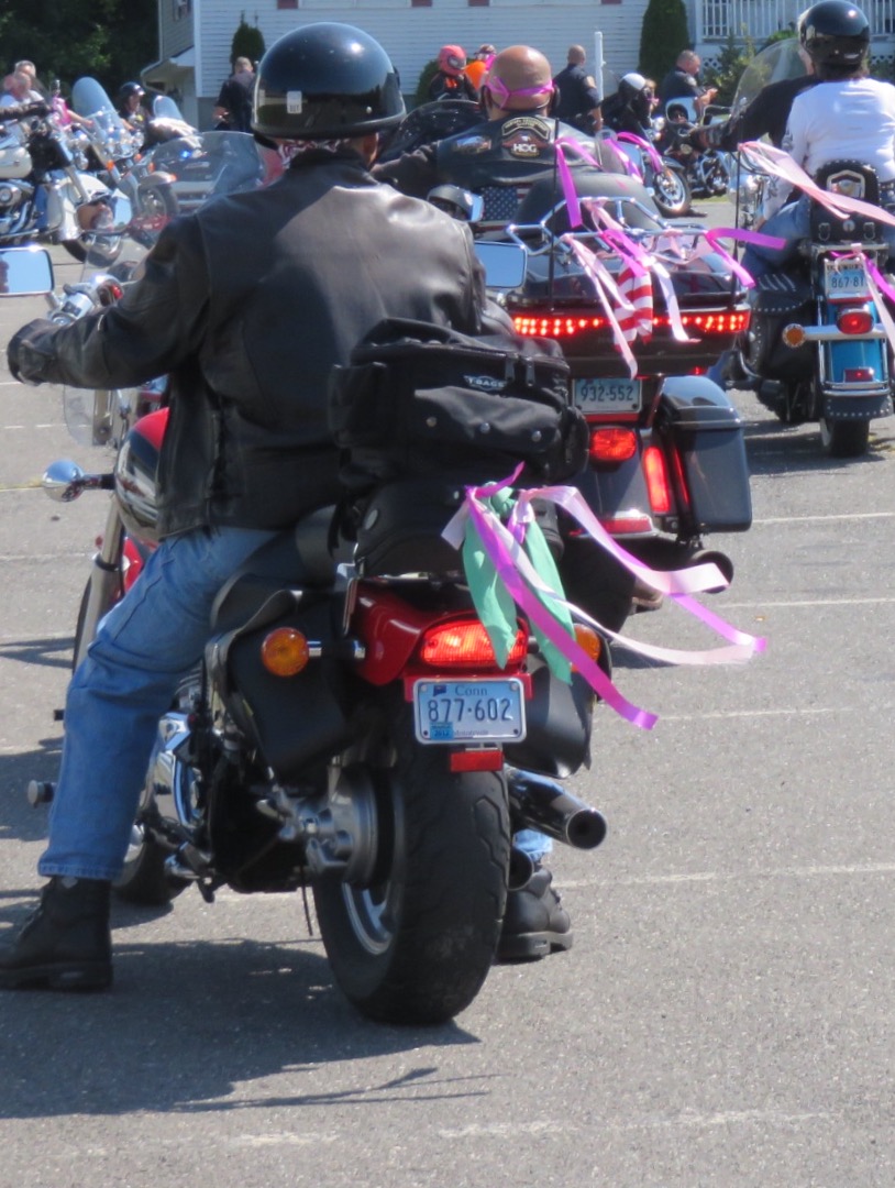 Motorcyclist with pink ribbons streaming from his bike