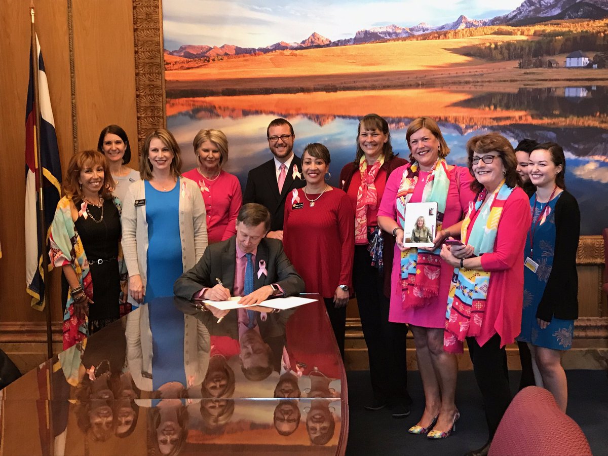 Colorado Governor John Hickenlooper signing the density reporting bill, surrounded by legislators and advocates