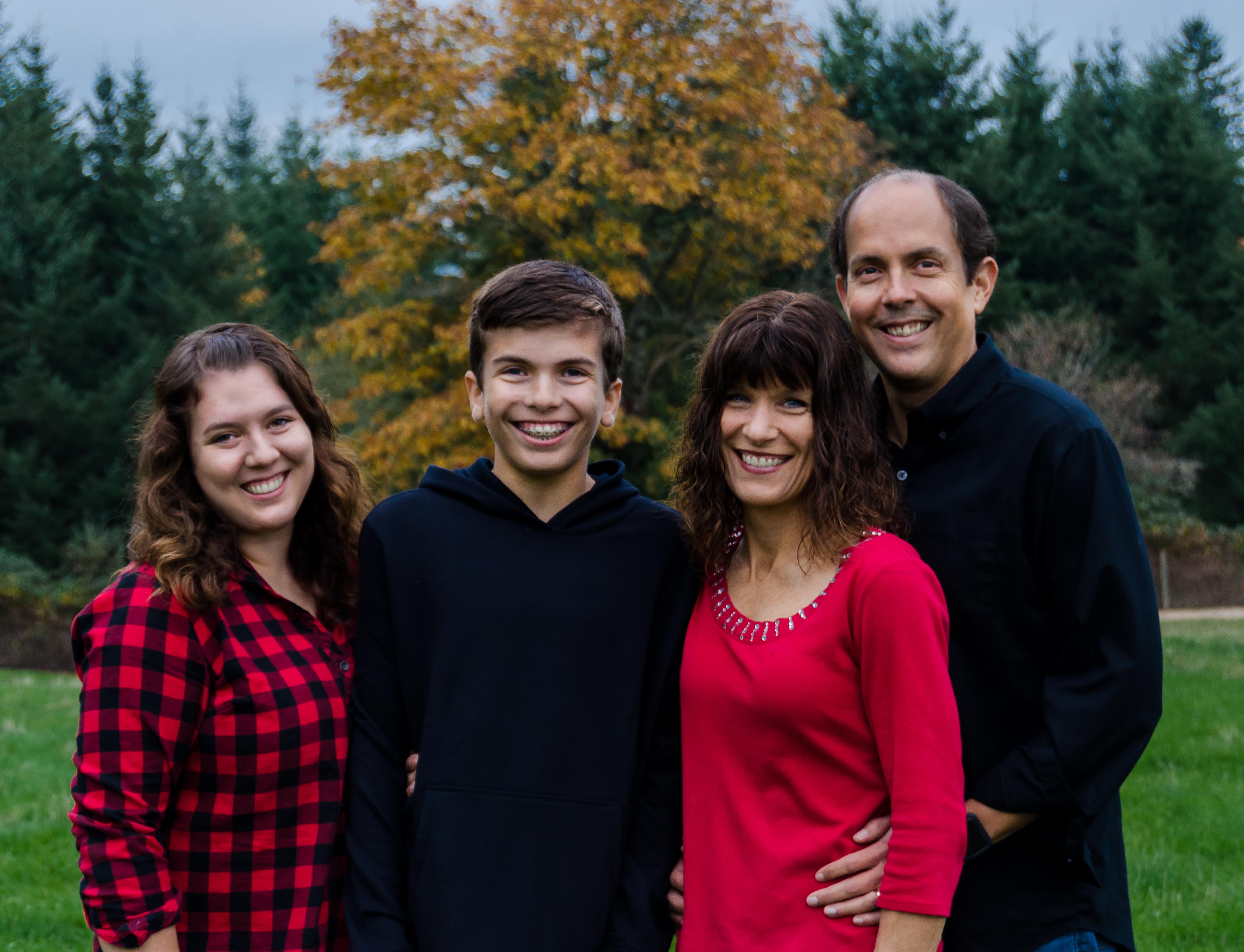 Tami smiling outdoors with her husband and two children