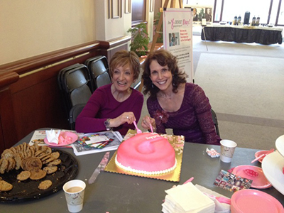 Jan Kritzman and Dr. Cappello cutting a pink cake at Are You Dense Day