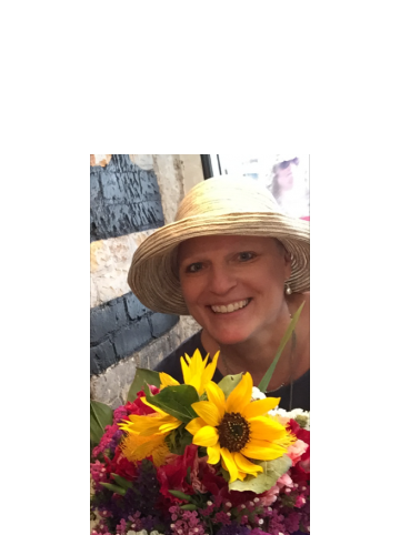 Gail in a sun hat, holding a bouquet of sunflowers
