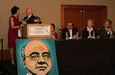 Award presentation at a Hyatt Regency Chicago podium, with panelists seated at the table beside it