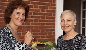 Sandy and her sister Carol outside a brick house