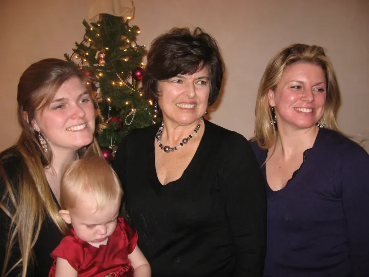 Kathy with family, including a baby, by a Christmas tree