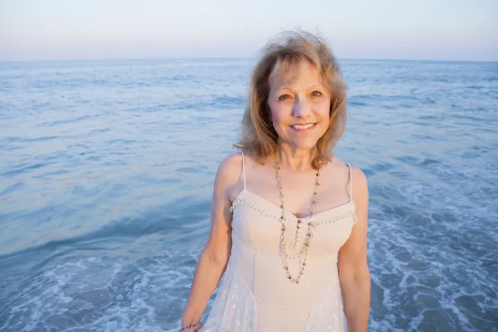 Jean standing at the water's edge on a beach